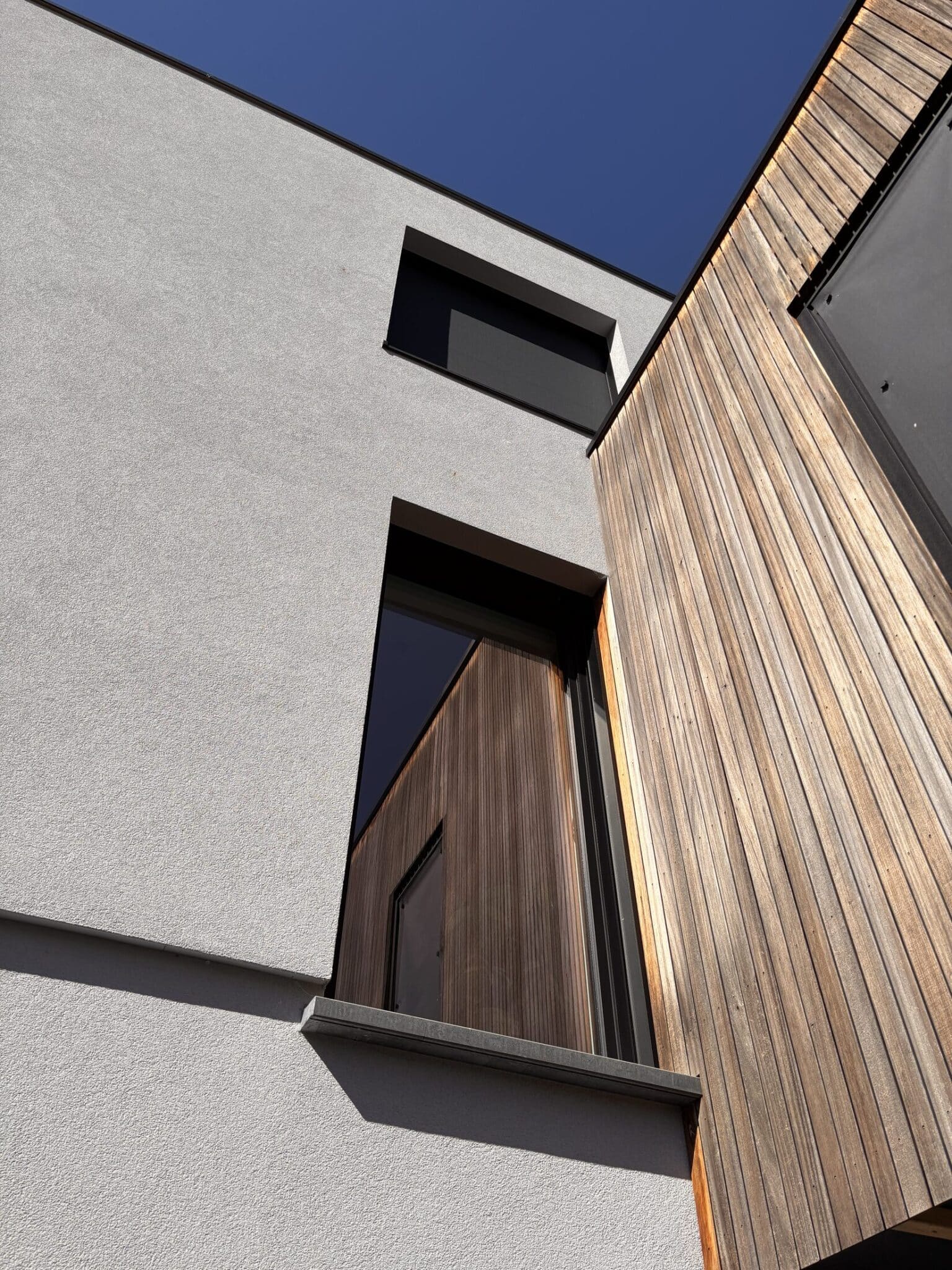 Façade moderne en bois et enduit avec grandes fenêtres, exemple de réalisation Monsieur Pode