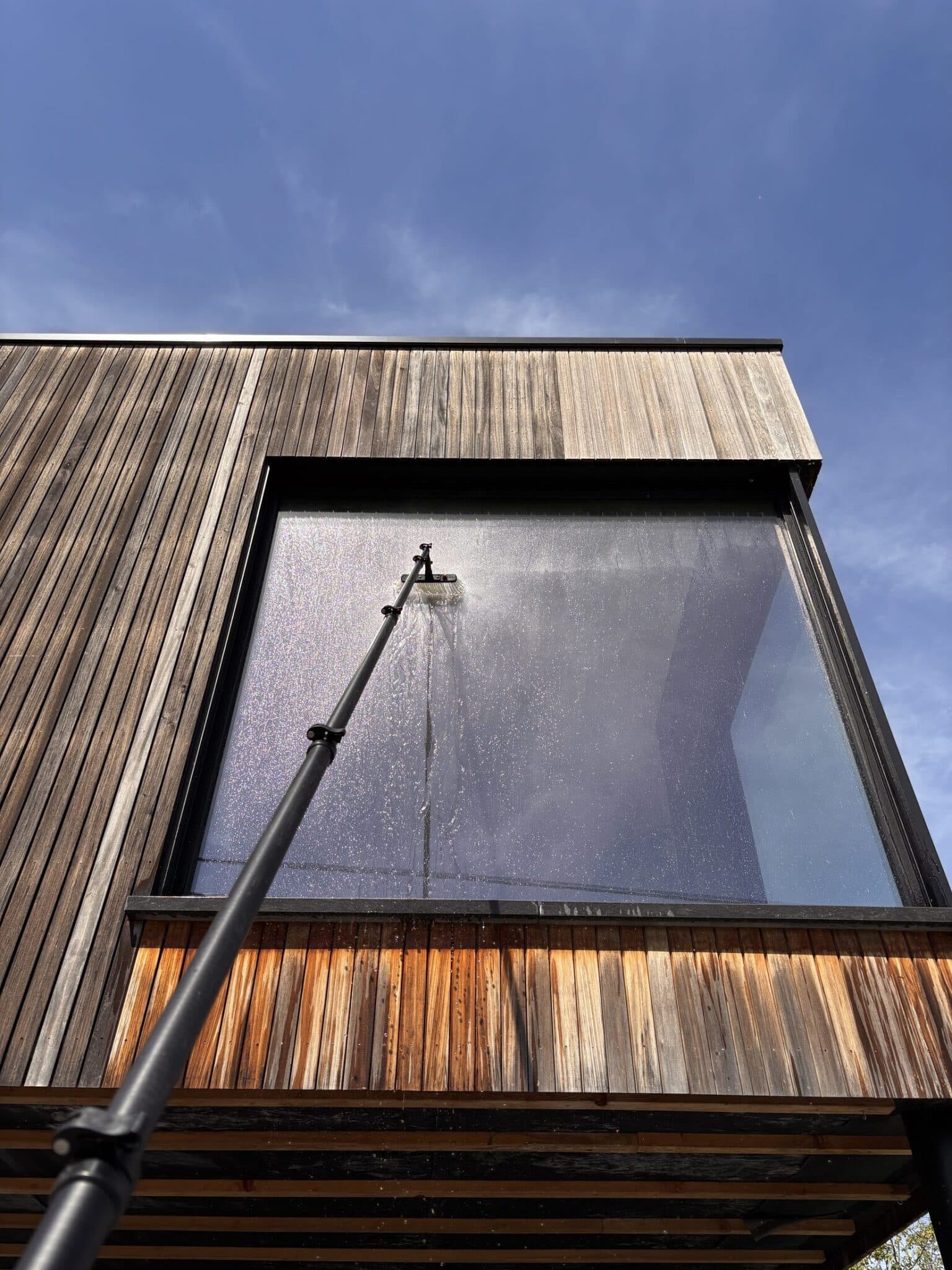 Nettoyage de vitre en hauteur sur une façade en bois par Monsieur Pode, à l'aide d'une perche télescopique